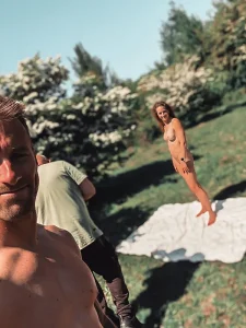 Selfie van een fotograaf met op de achtergrond een naaktmodel tijdens een buitenshoot.