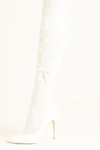 Witte laarzen op een lichte achtergrond als detail voor een sensuele fotoshoot.